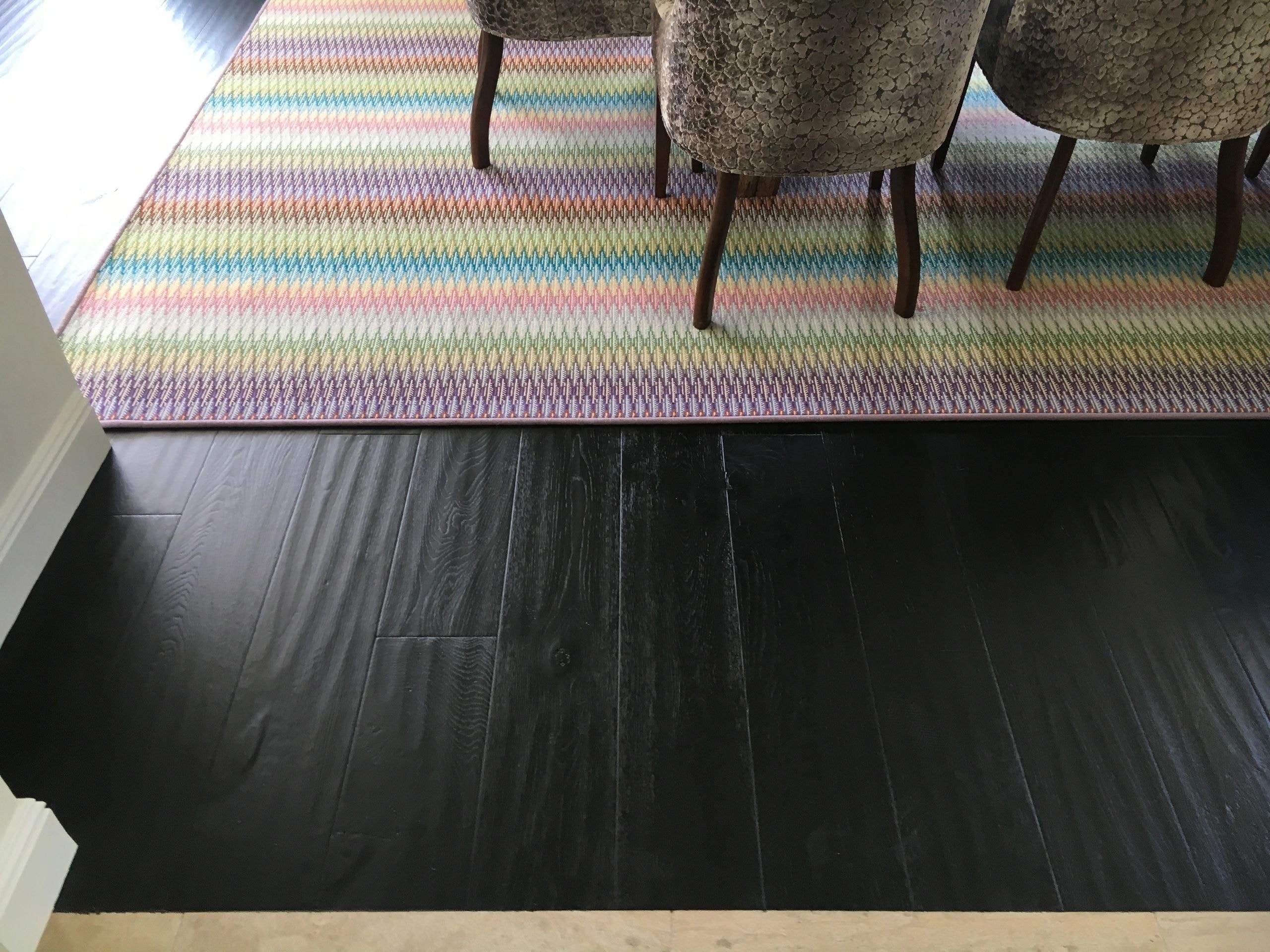 Dark ebony stained hardwood floor with colorful rug